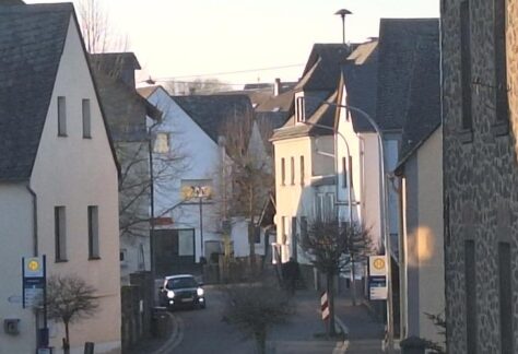 Blick durch eine enge Dorfstraße mit traditionellen Steinhäusern bei Dämmerung oder frühem Morgen