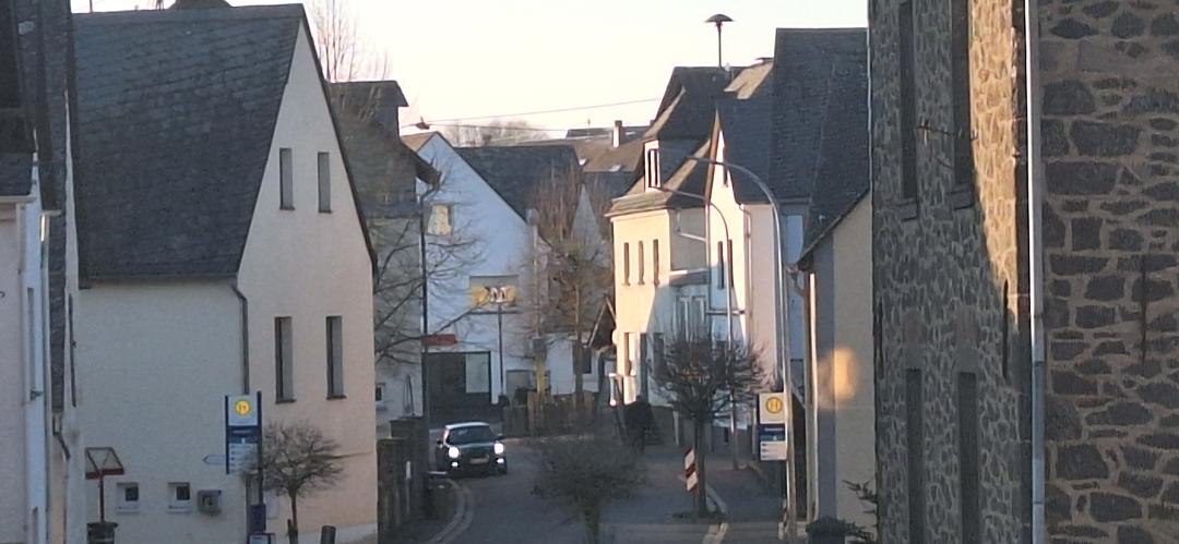 Blick durch eine enge Dorfstraße mit traditionellen Steinhäusern bei Dämmerung oder frühem Morgen