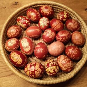 Korb mit kunstvoll dekorierten Ostereiern in Rottönen mit gelben Mustern und Schriftzügen "Frohe Ostern" in sorbischer Tradition